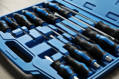 Set of screwdrivers in open toolbox on wooden table, closeup