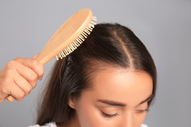 Woman with hair loss problem on grey background, closeup. Trichology treatment