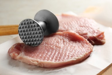 Photo of Cooking schnitzel. Raw pork chops and meat mallet on wooden board, closeup