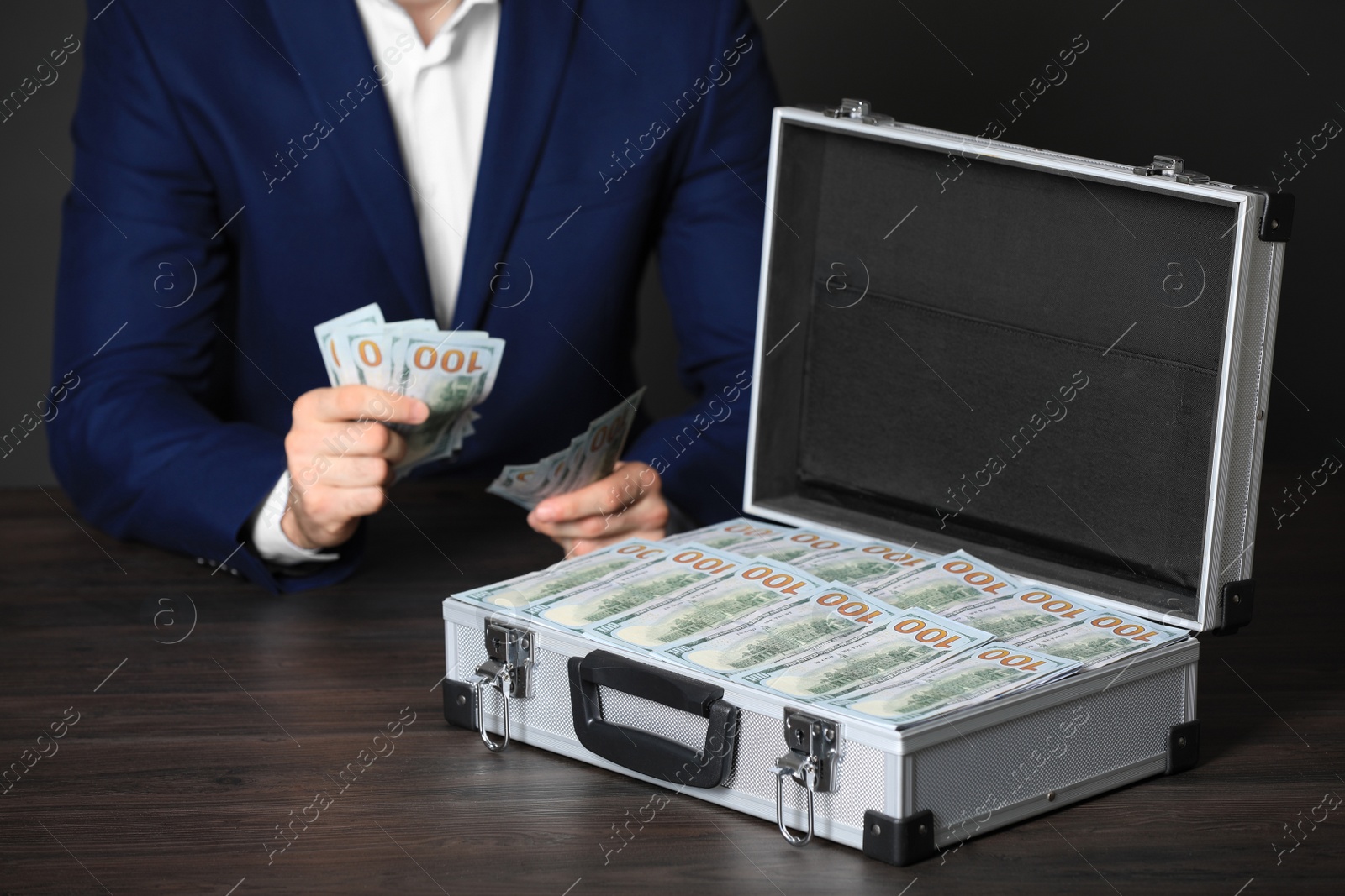 Photo of Businessman with case of dollar bills at wooden table, closeup