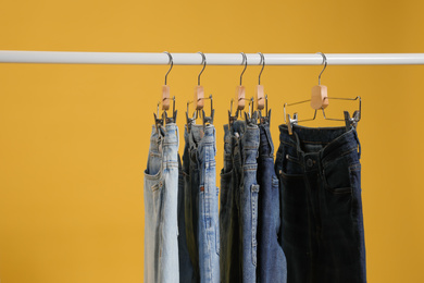 Photo of Rack with different jeans on yellow background