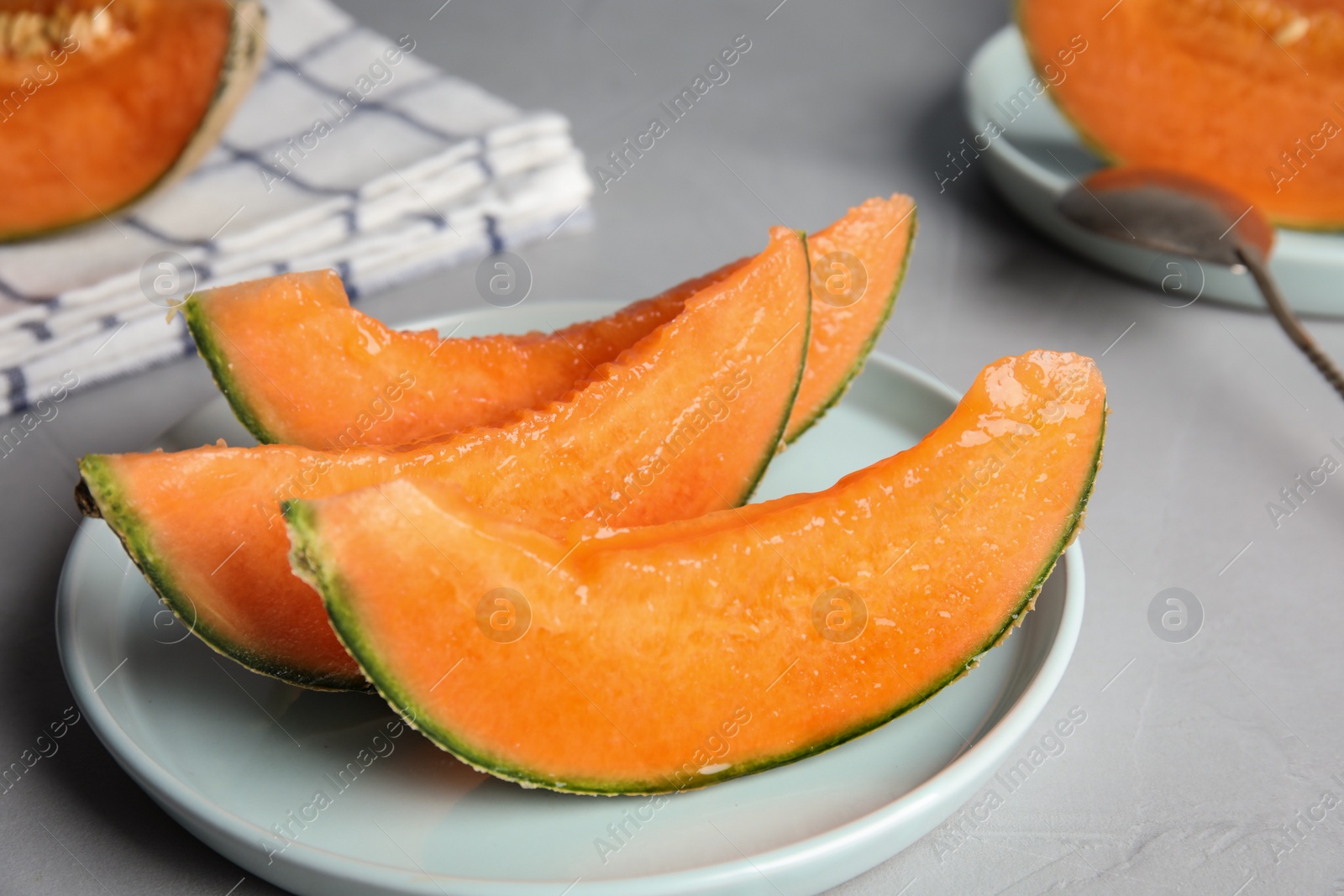 Photo of Slices of ripe cantaloupe melon in plate on grey table