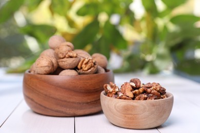 Bowls with walnuts on white wooden table outdoors