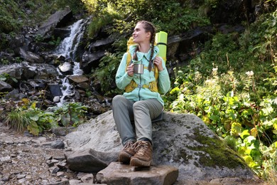 Photo of Tourist with cup near waterfall in mountains