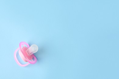 Photo of One new baby pacifier on light blue background, top view. Space for text