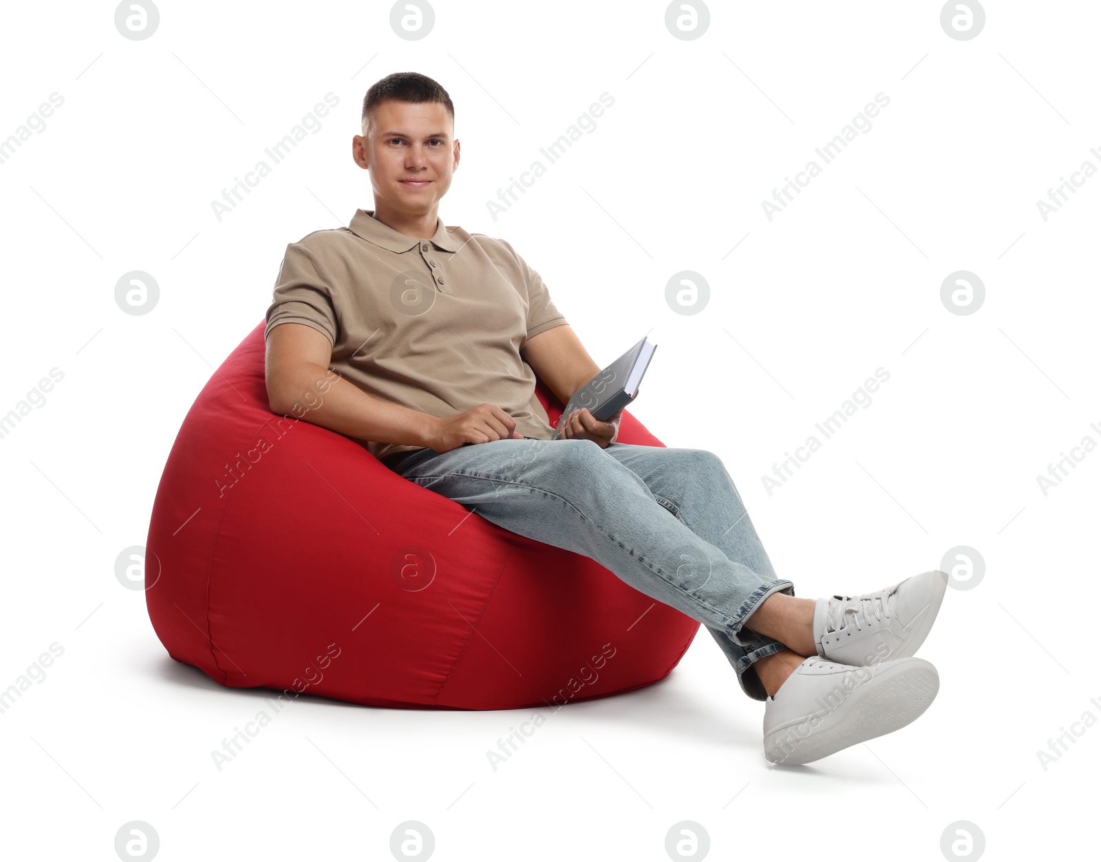 Photo of Handsome man with book sitting on red bean bag chair against white background