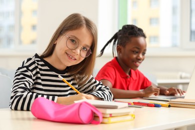 Photo of Smiling girl with her classmate studying in classroom at school