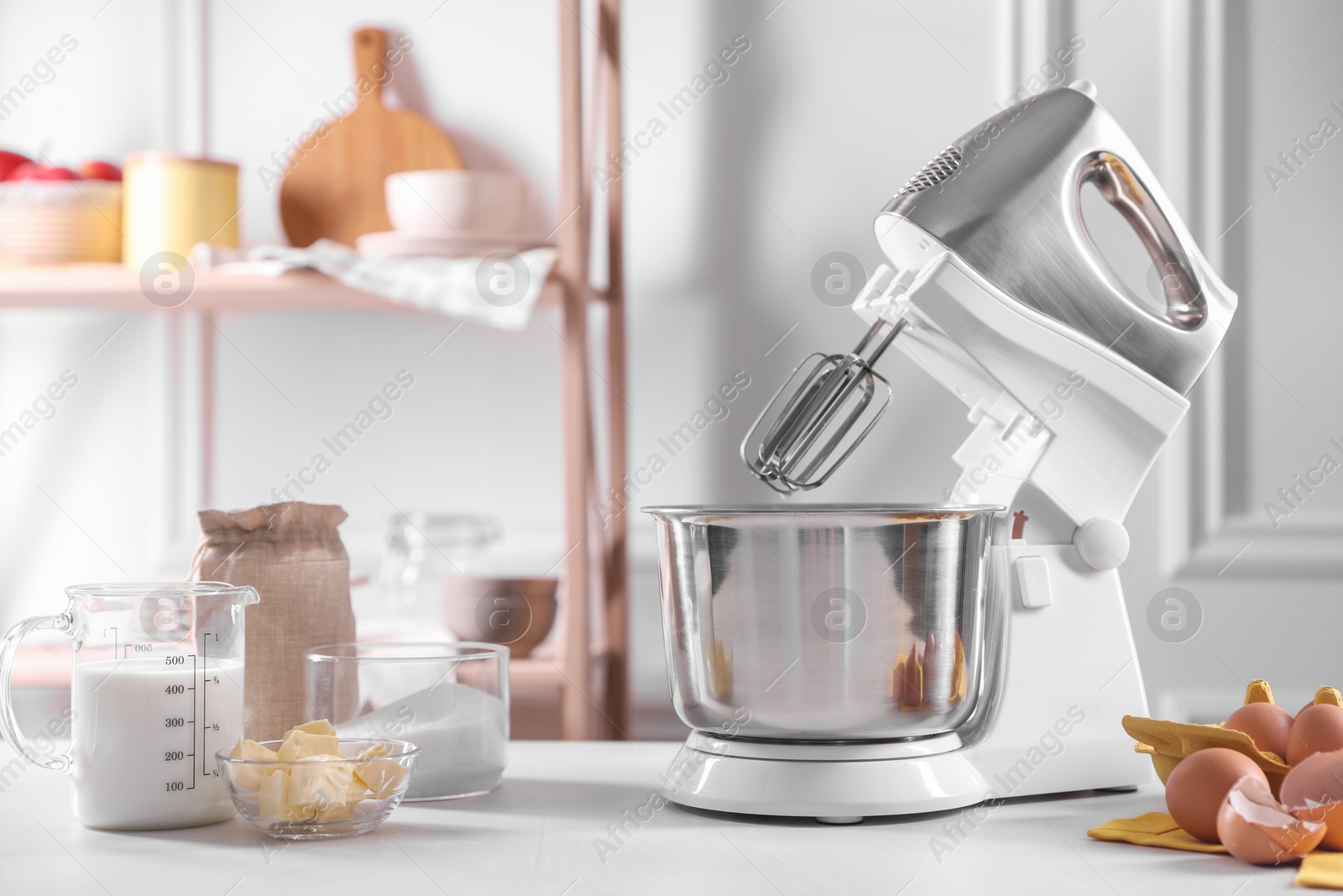 Photo of Modern stand mixer and ingredients for dough on white table indoors