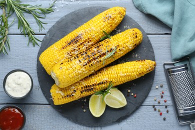 Flat lay composition with tasty grilled corn on light blue wooden table