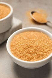 Photo of Brown sugar in bowl on grey table, closeup