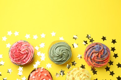 Delicious cupcake with bright cream and shiny confetti on yellow background, flat lay. Space for text