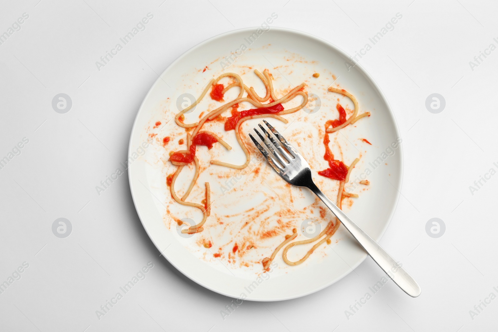 Photo of Dirty plate with food leftovers and fork on white background, top view