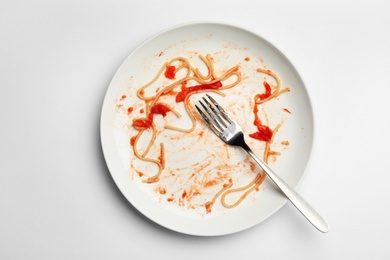 Photo of Dirty plate with food leftovers and fork on white background, top view