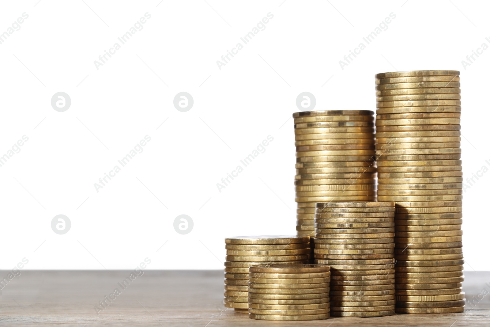 Photo of Many golden coins stacked on wooden table against white background, space for text