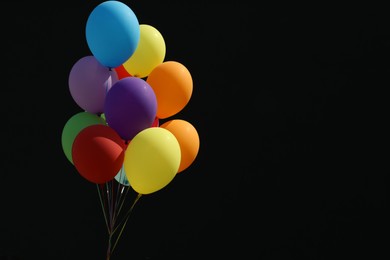 Photo of Bunch of colorful balloons on black background. Space for text