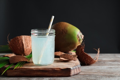Photo of Beautiful composition with glass jar of coconut water on table against dark background