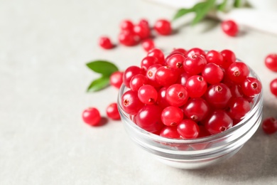 Photo of Fresh cranberry in bowl on light table, space for text