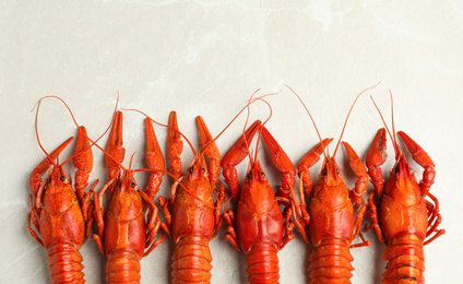 Photo of Delicious boiled crayfishes on light grey marble table, flat lay