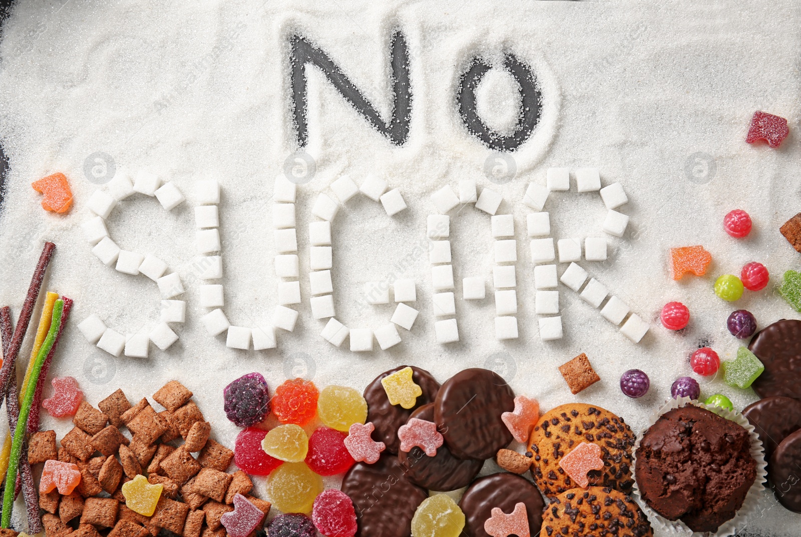 Photo of Composition with phrase NO SUGAR and sweets on sugar sand