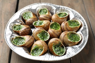 Delicious cooked snails on wooden table, closeup