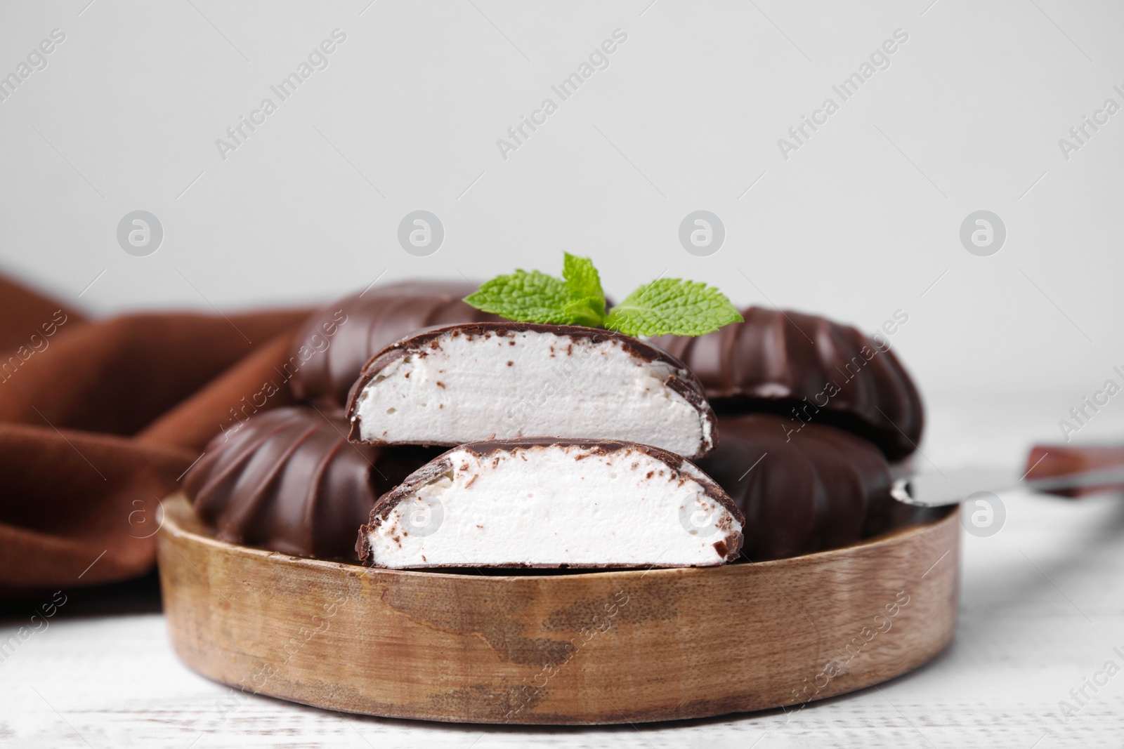 Photo of Delicious chocolate covered marshmallows with mint on white wooden table