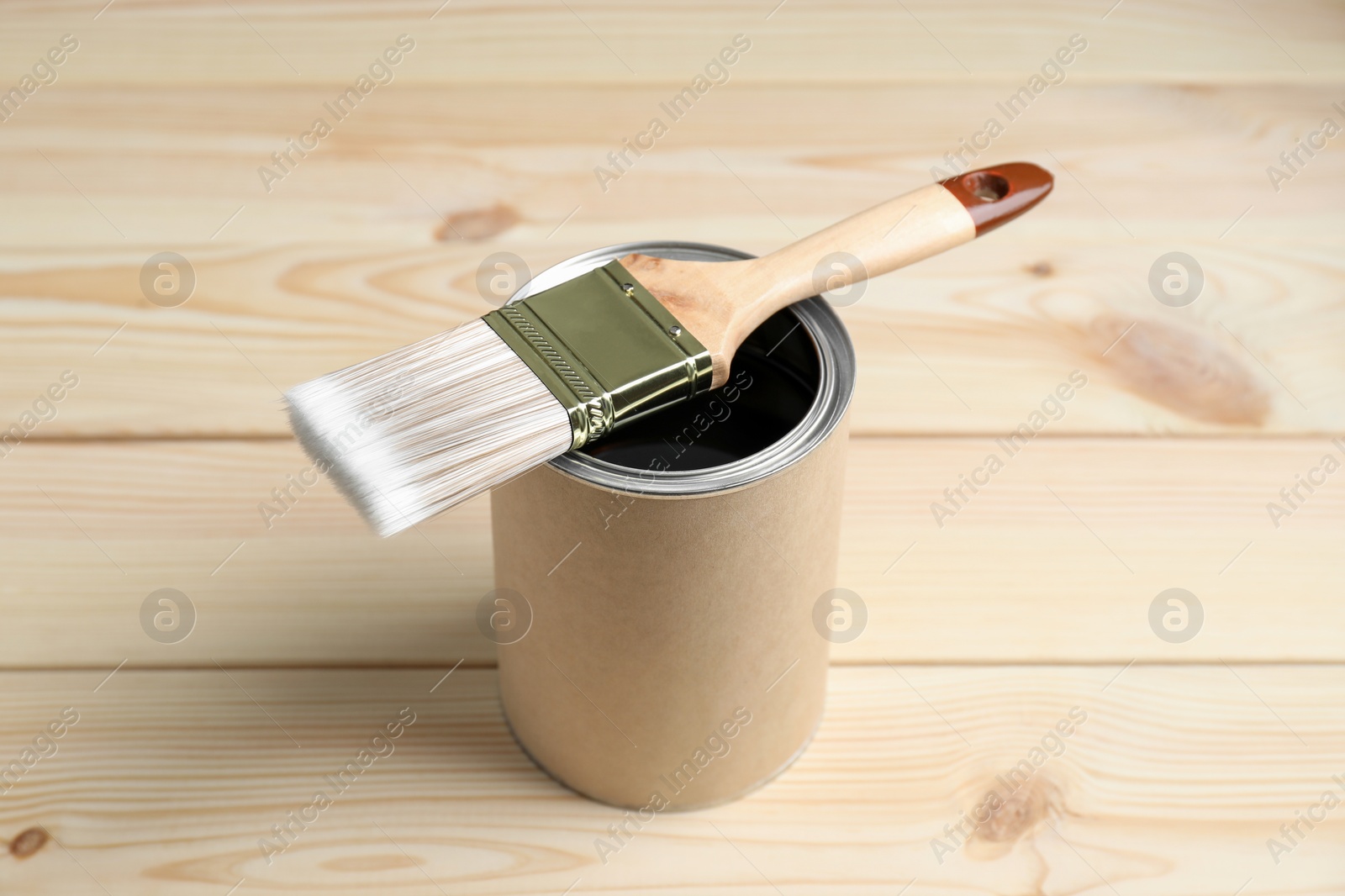 Photo of Can and brush with wood stain on wooden surface
