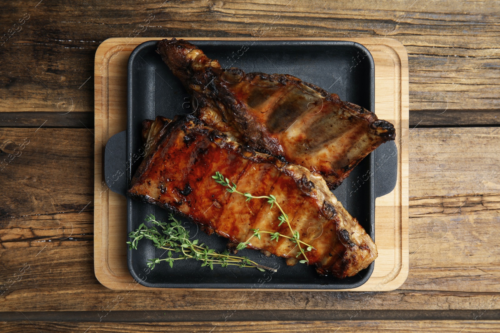 Photo of Tasty grilled ribs on wooden table, top view