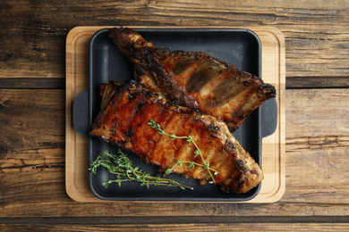 Tasty grilled ribs on wooden table, top view