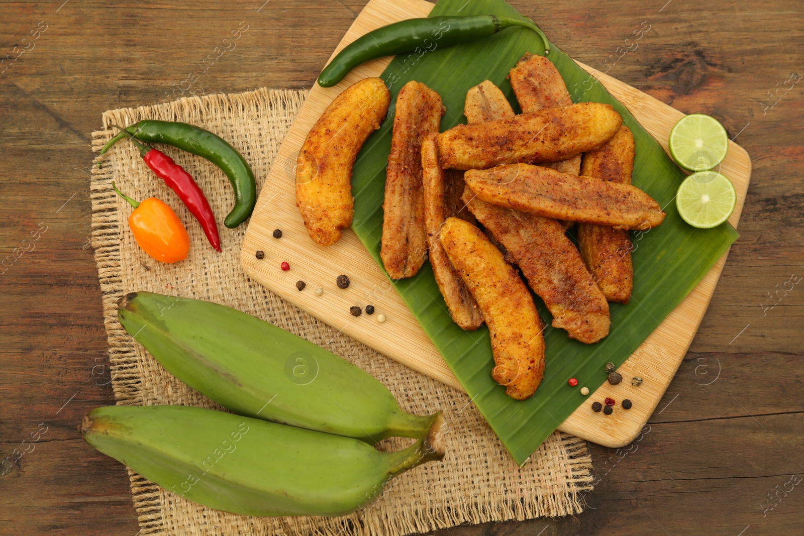 Photo of Delicious fried bananas, fresh fruits and different peppers on wooden table, flat lay