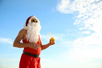 Photo of Santa Claus in beach outfit with cocktail outdoors, space for text. Christmas vacation