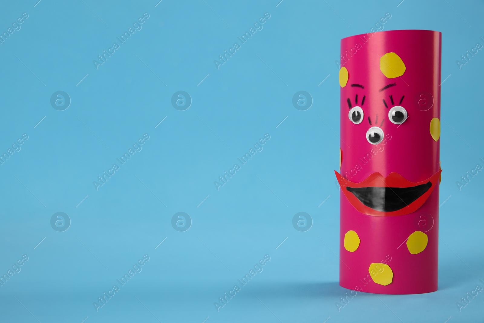 Photo of Funny pink monster on light blue background, space for text. Halloween decoration