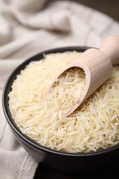 Bowl and scoop with raw rice on table, closeup