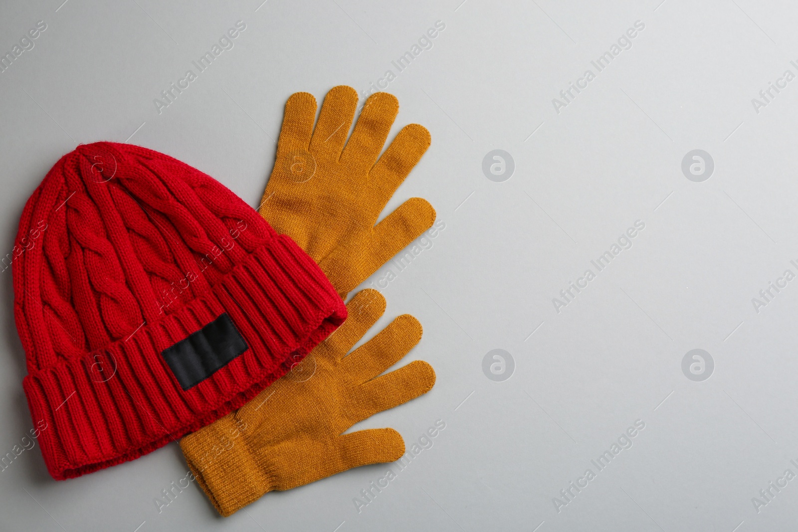 Photo of Woolen gloves and hat on light grey background, flat lay. Space for text