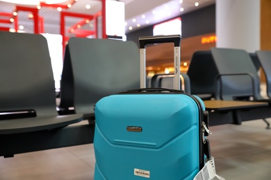 Photo of ISTANBUL, TURKEY - AUGUST 6, 2019: Bright modern suitcase near bench in airport