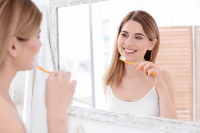 Young woman brushing her teeth in bathroom