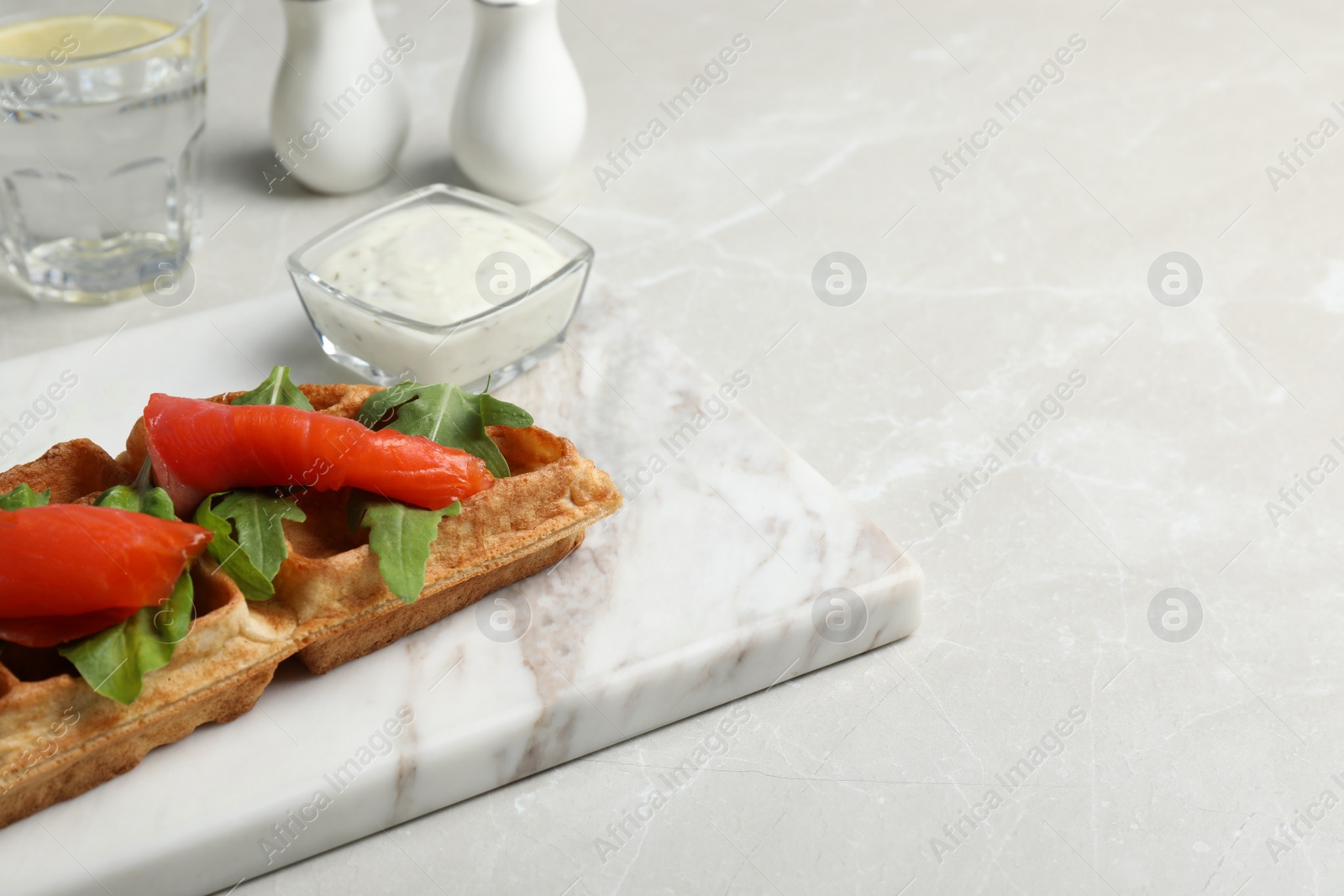Photo of Fresh Belgian waffle with salmon and arugula on white table, space for text