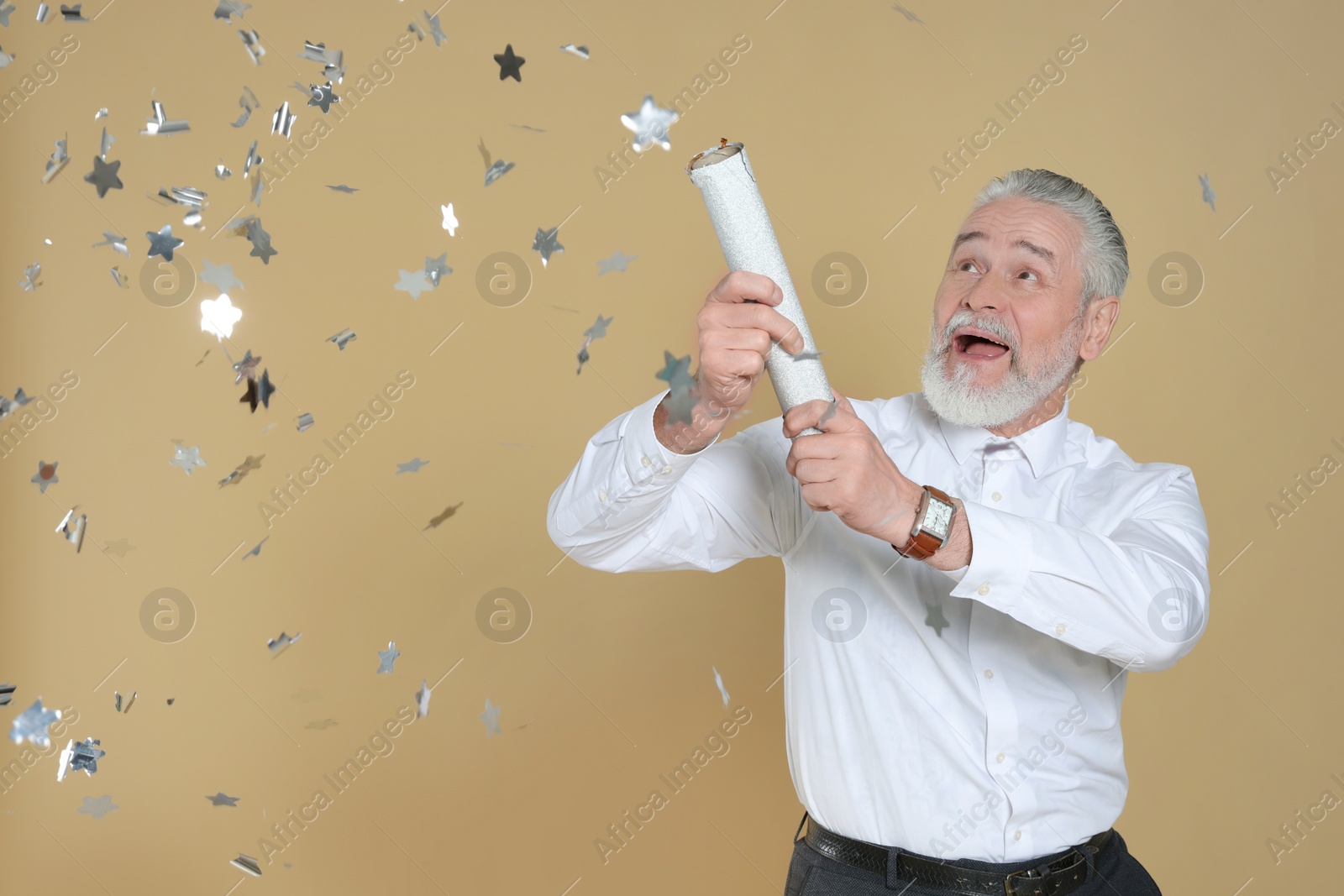 Photo of Emotional man blowing up party popper on beige background