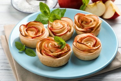 Photo of Freshly baked apple roses on white wooden table. Beautiful dessert