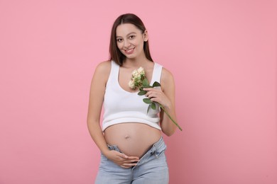 Beautiful pregnant woman with roses on pink background