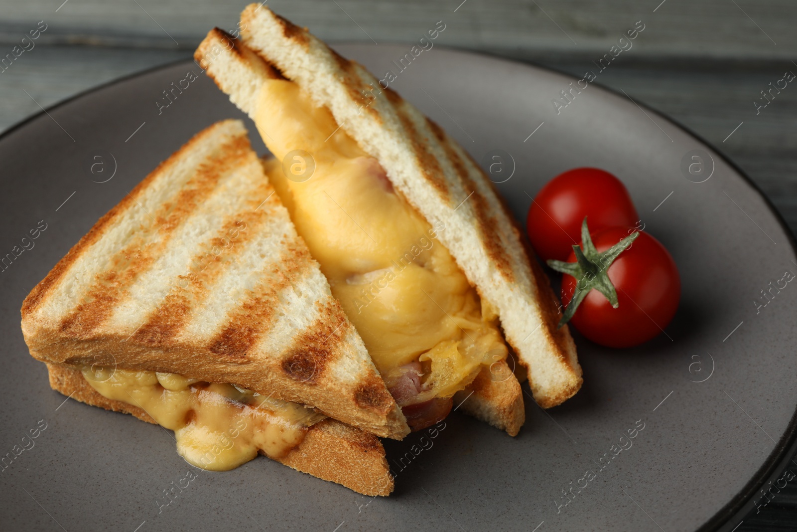 Photo of Tasty sandwiches with ham, melted cheese and tomatoes on table, closeup