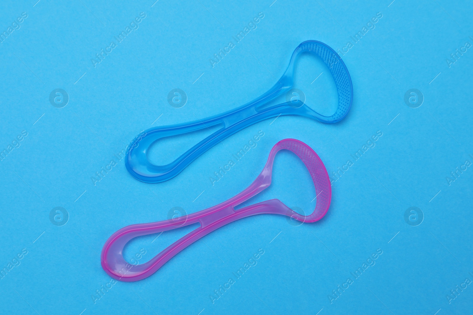 Photo of Tongue cleaners on blue background, flat lay