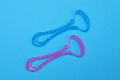 Photo of Tongue cleaners on blue background, flat lay