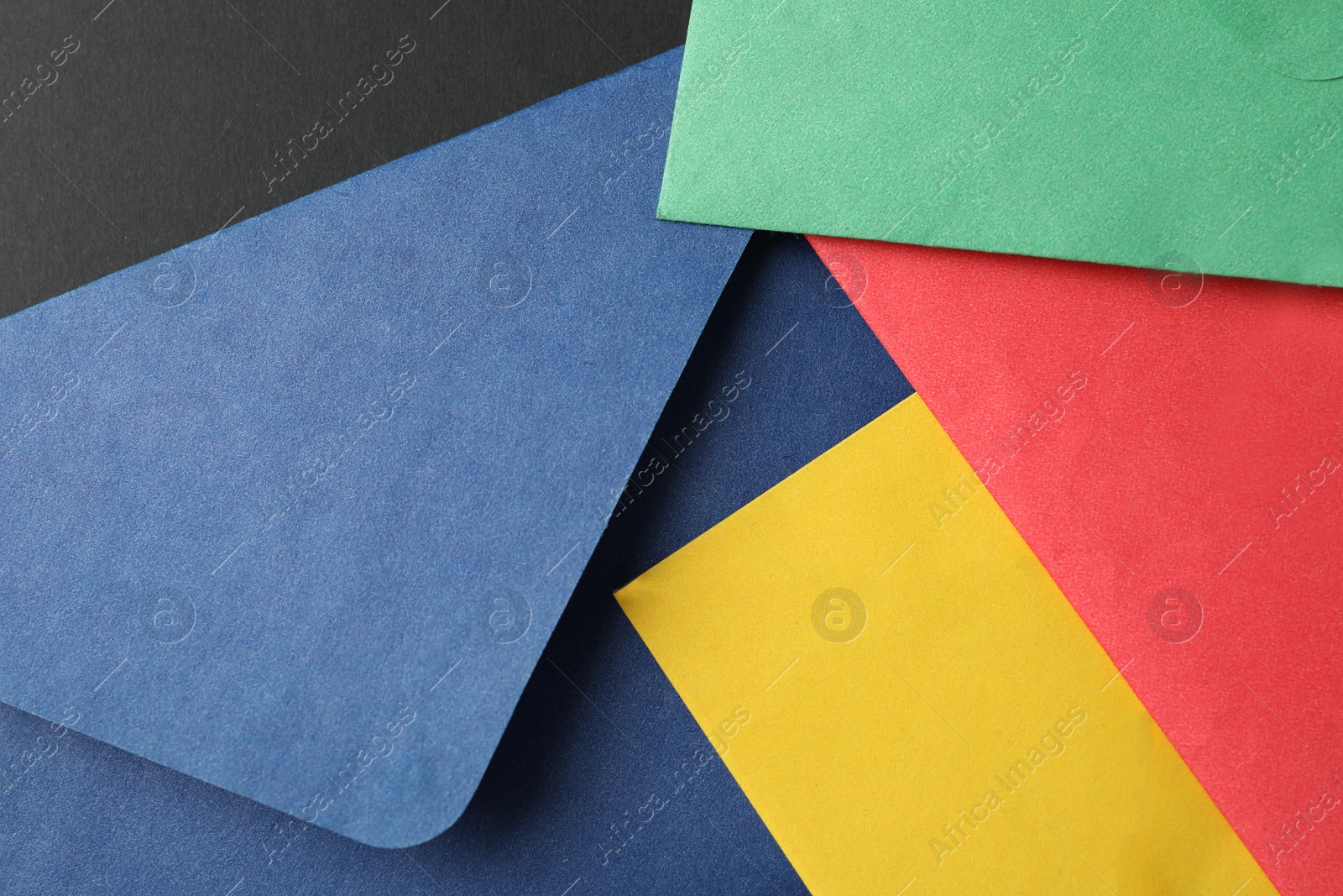 Photo of Colorful paper envelopes on black background, closeup