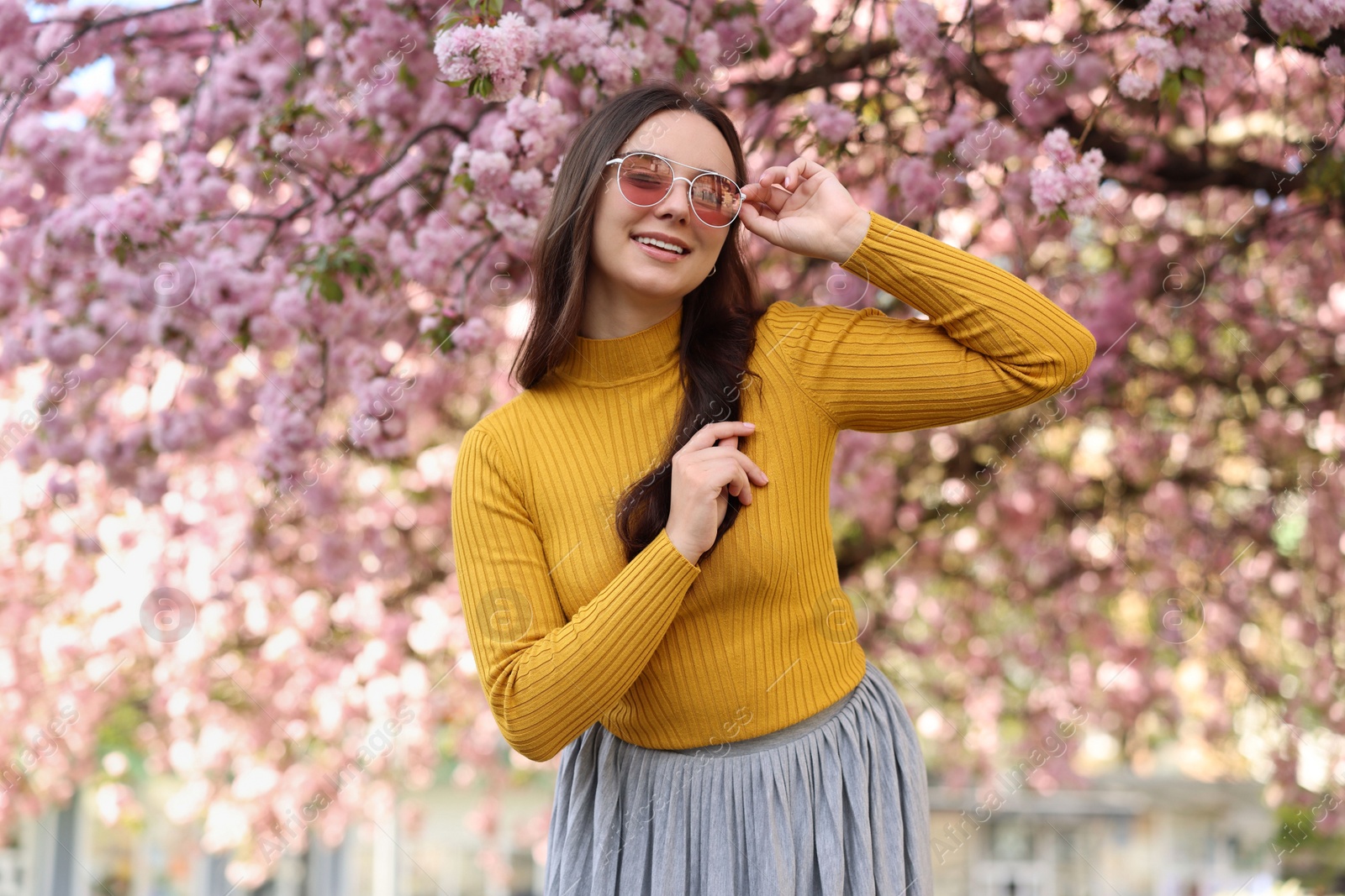 Photo of Beautiful woman in sunglasses near blossoming tree on spring day