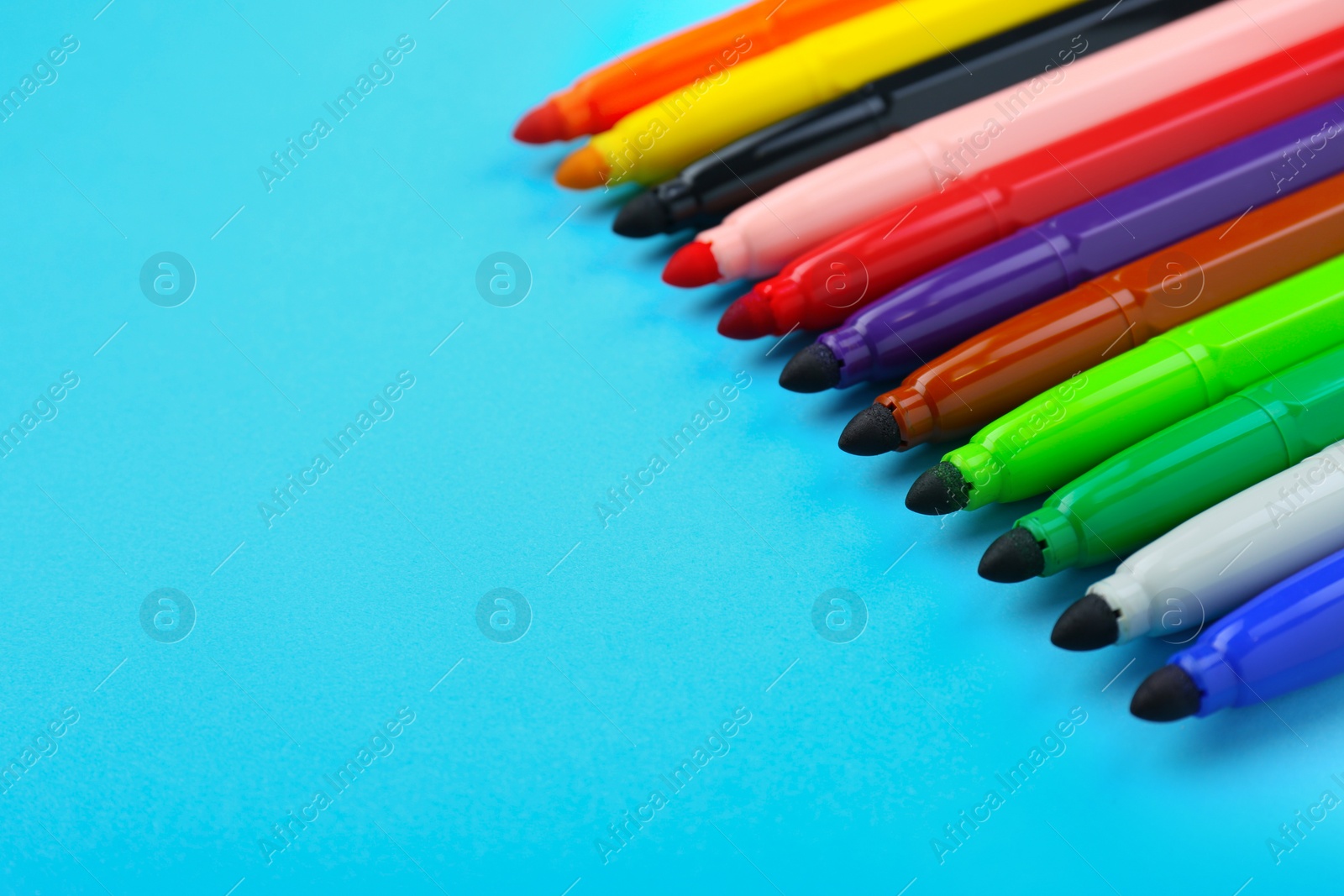 Photo of Many different colorful markers on light blue background, closeup. Space for text