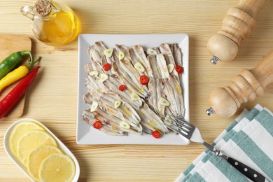 Photo of Tasty pickled anchovies served on wooden table, flat lay