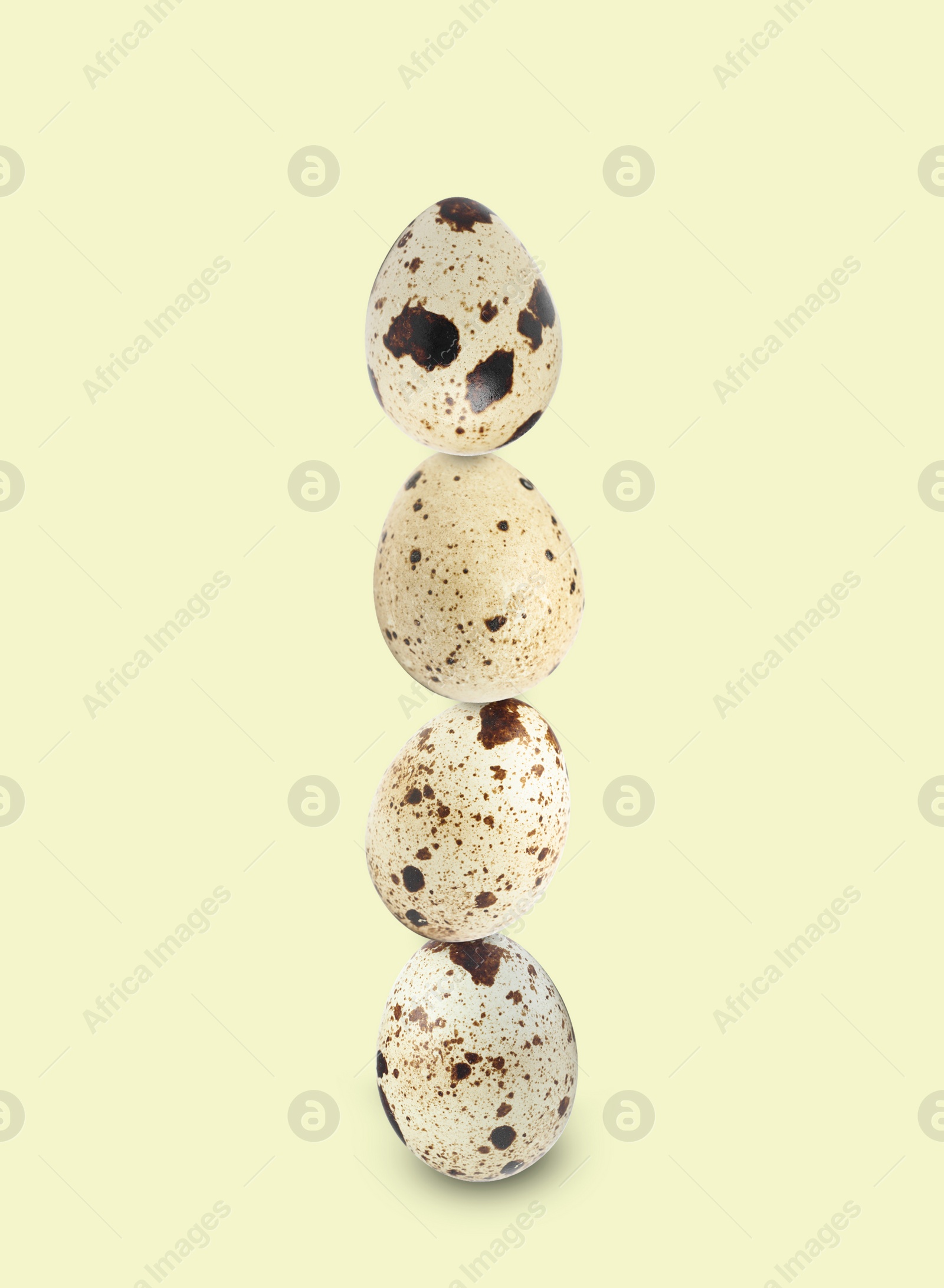 Image of Stacked speckled quail eggs on light beige background