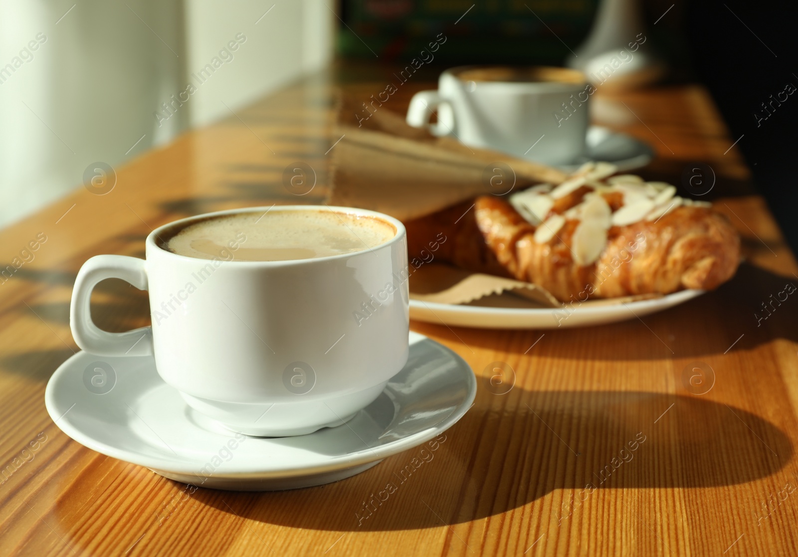 Photo of Cup of fresh aromatic coffee and croissant at table in cafe