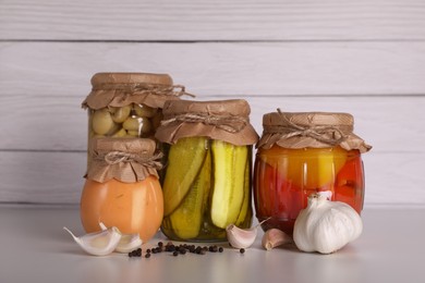 Photo of Jars with different preserved vegetables and fresh spices for canning on light grey table