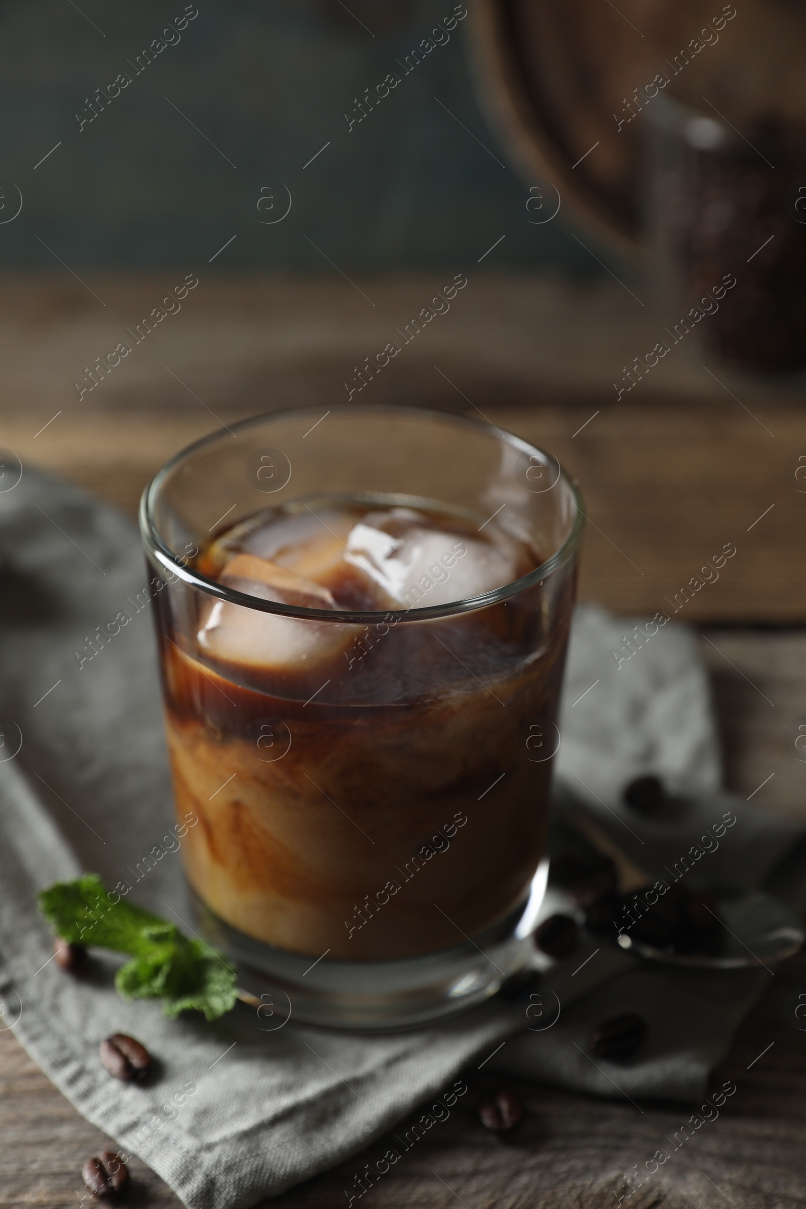 Photo of Glass of delicious iced coffee with milk, mint and beans on wooden table